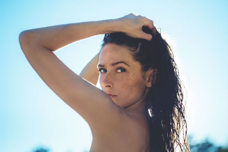 beautiful woman with freckles with sun right behind her